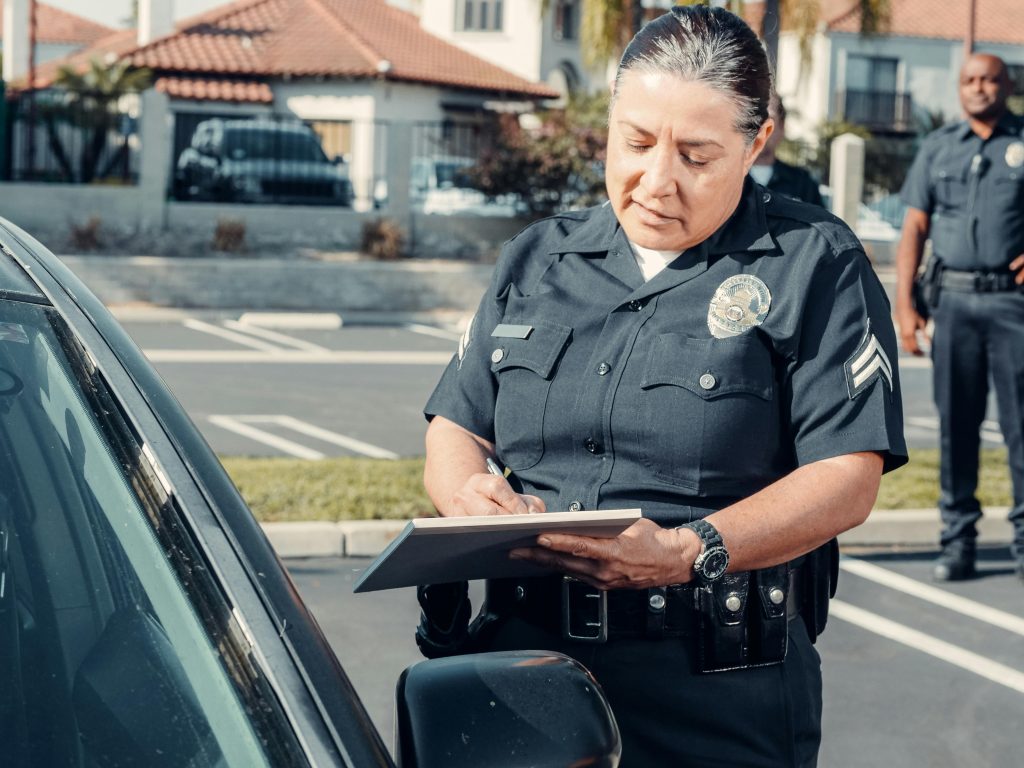 Police officer writing a citation beside a car during a traffic stop